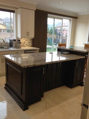 Luxury kitchen with large black island featuring granite countertop, light cabinetry, and windows overlooking outdoor area