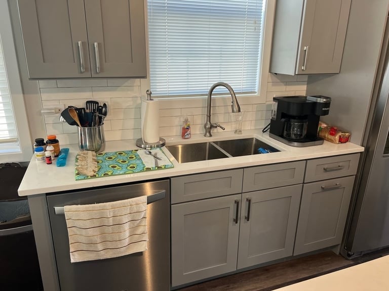 Modern gray kitchen with white countertop, stainless steel sink, faucet, and appliances including coffee maker and utensil holder