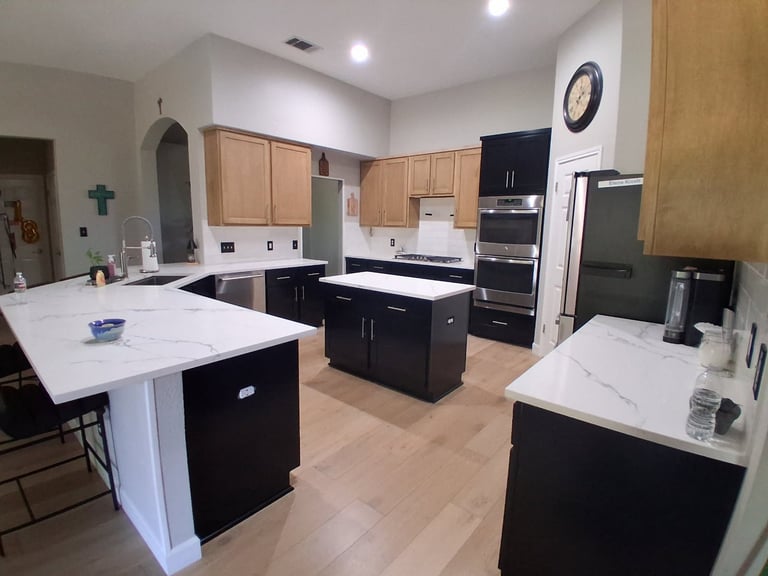 Modern kitchen with white and black cabinetry, white quartz countertops, stainless steel appliances, and large center islands